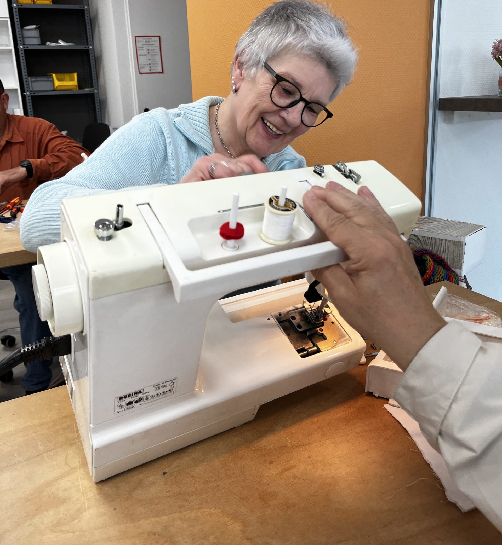 Eine ältere Frau begutachtet eine Nähmaschine.