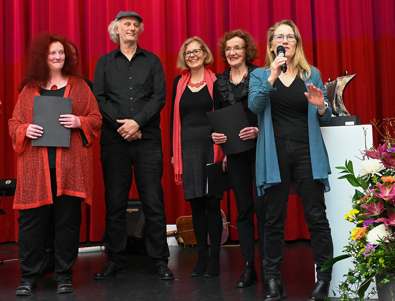 Vier Personen stehen während der Preisverleihung auf der Bühne. Eine hält ein Mikrofon in der Hand.