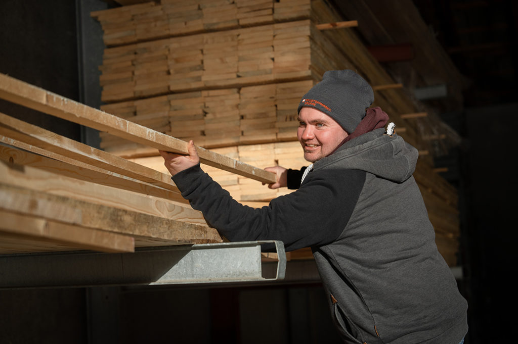 Tim Wunder beim Sortieren von Holzlatten im Lager