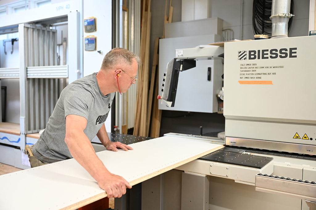 Thorsten Werner schiebt ein Brett in die Kantenanleimmaschine