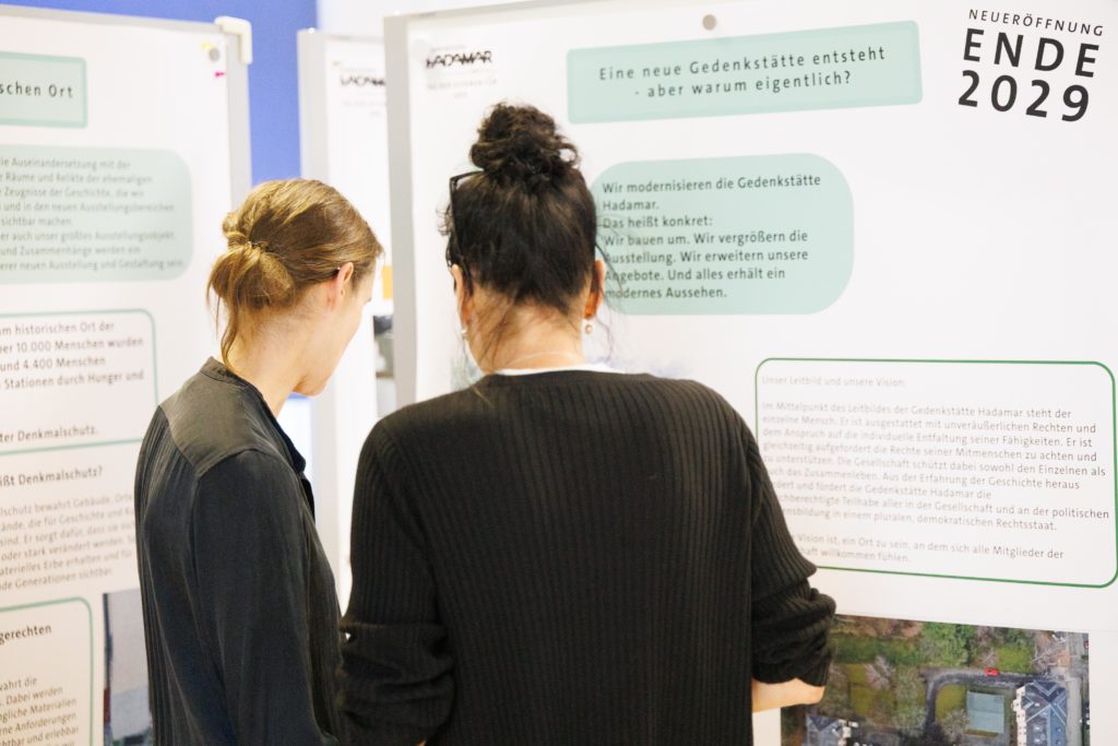 Zwei Frauen studieren interessiert die Infoplakate. 