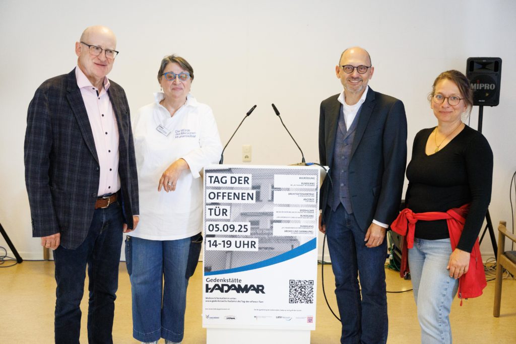 Einige Beteiligte der Veranstaltung stehen für ein Gruppenfoto neben dem Rednerpult.