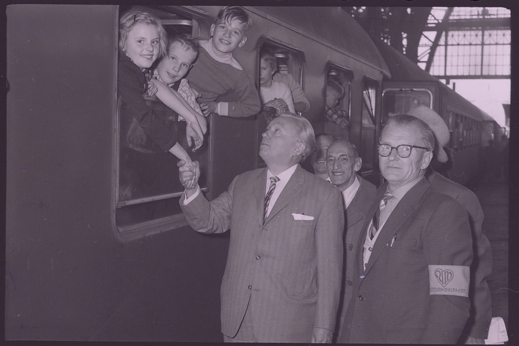 schwarzweiß-Fotografie: Verabschiedung von Kindern zur Erholung in Cavigliano, Schweiz durch Landesdirektor Hermann Schaub (Mitte) am Hauptbahnhof in Frankfurt am Main 1959 (LWV-Archiv, F 060, Nr. 883)