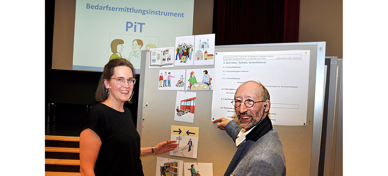 LWV-Mitarbeiterin Judith Wege steht mit Björn Schneider vom Selbstvertretungs-Rat der Lebenshilfe Frankfurt vor einer Tafel mit Bildern zur Leichten Sprache.