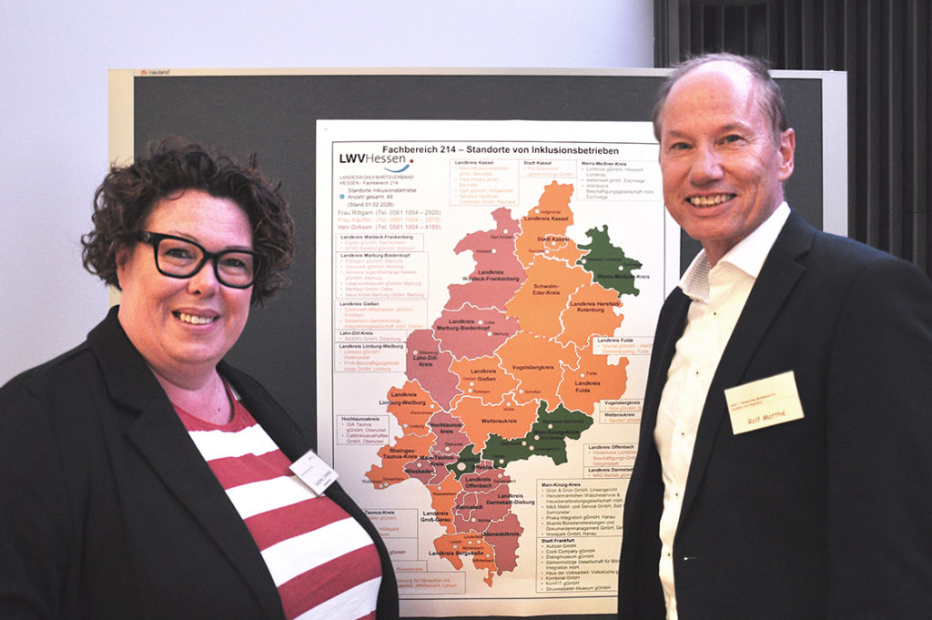 Ein Mann und eine Frau stehen vor einer Hessenkarte.